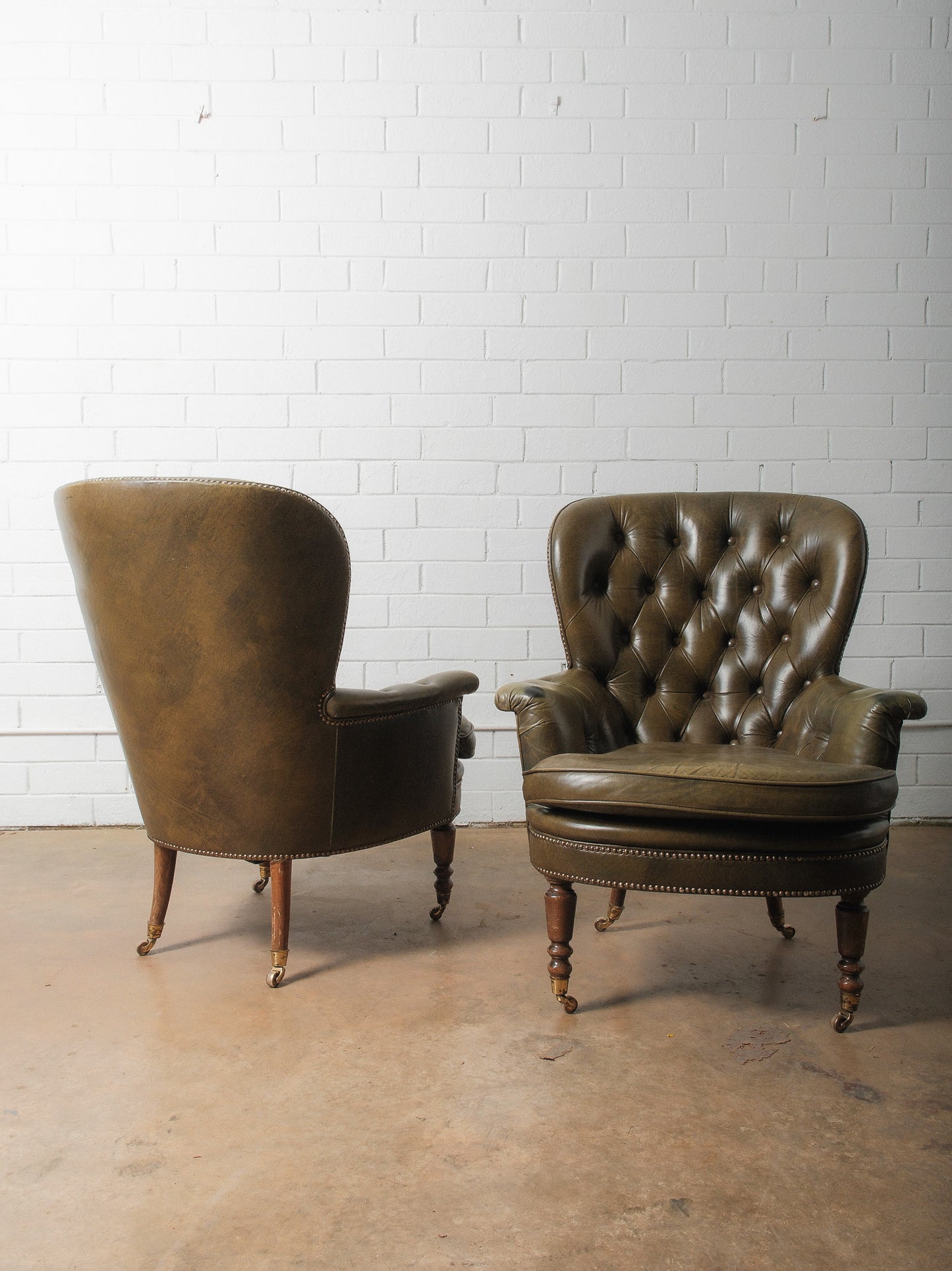Pair of Vintage Tufted Leather Club Chairs with Brass Casters and Turned Legs