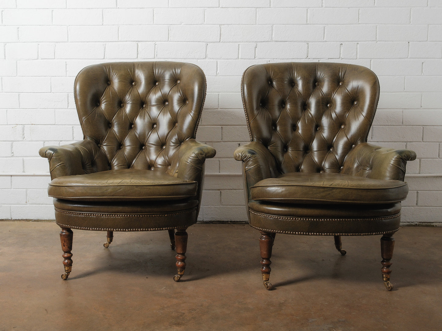 Pair of Vintage Tufted Leather Club Chairs with Brass Casters and Turned Legs